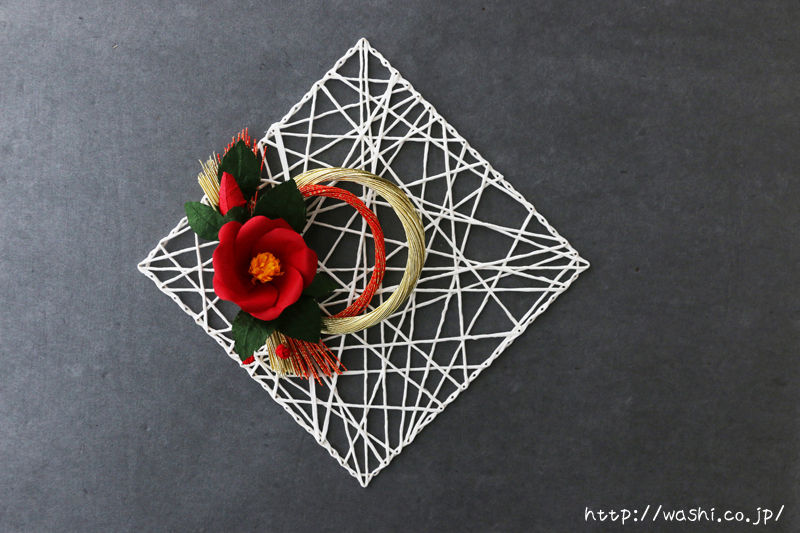 和紙の椿を使ったお正月飾り。ベース部分は紙糸（白）で製作し、グレーの壁に合うアレンジに仕上げました。
