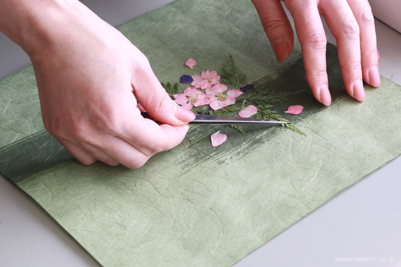 手染め和紙の上にピンセットで押し花を配置している制作風景